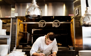 Chef in kitchen writing notes.